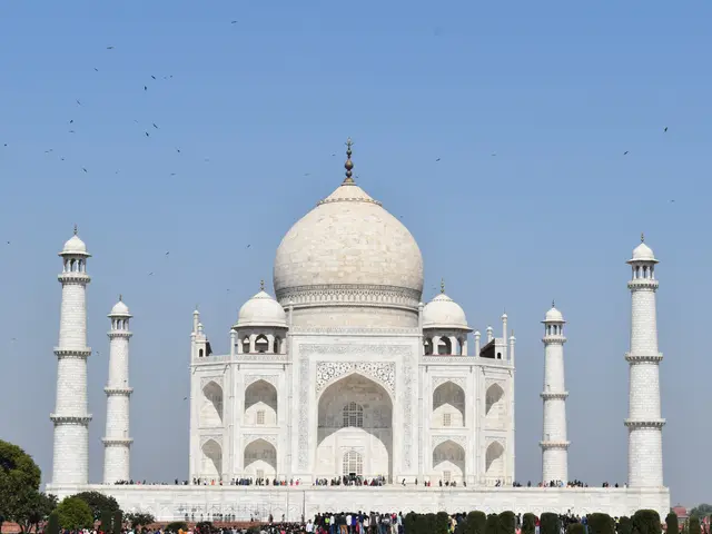 The image shows the majestic Taj Mahal in Agra, India, surrounded by lush green trees and plants,...