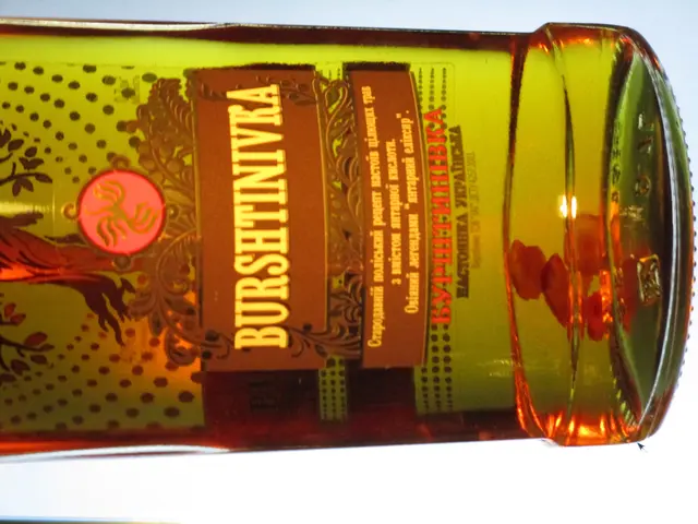 The image shows a bottle of olive oil sitting on top of a table. The bottle is filled with a...