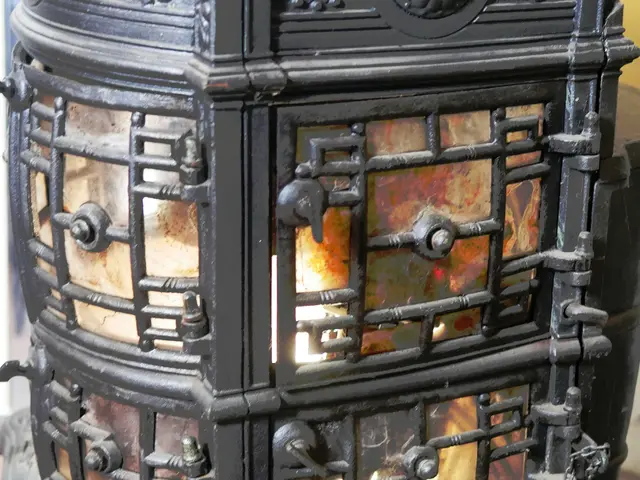 The image shows a black wood burning stove sitting atop a wooden floor, with a wall in the...