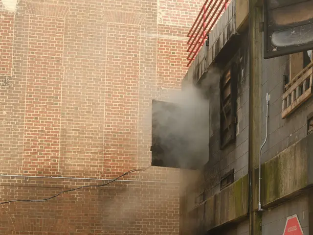 The image shows a group of firefighters working to put out a fire in a building. They are wearing...