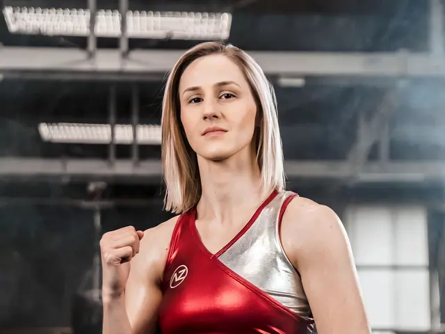 The image shows a woman in a red top and silver shorts standing in a gym, illuminated by lights and...