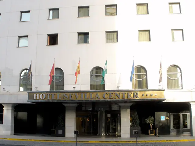 The image shows the Hotel Sevilla Center in Madrid, Spain. It is a large building with glass...