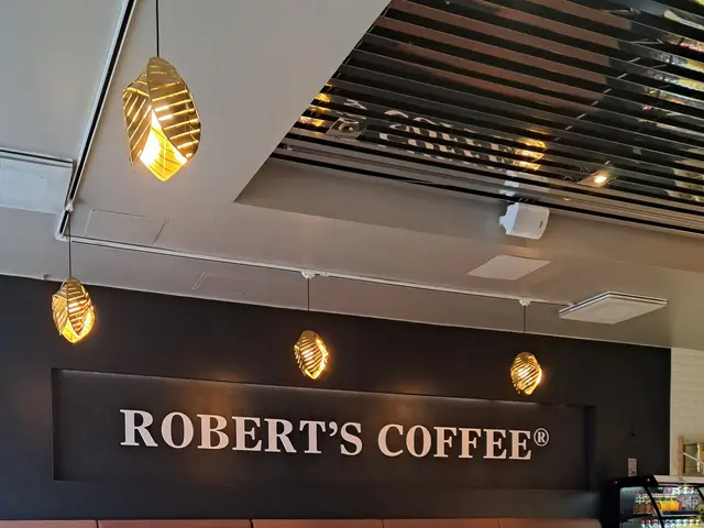 The image shows the interior of Robert's Coffee in London, England. There are chairs and tables on...